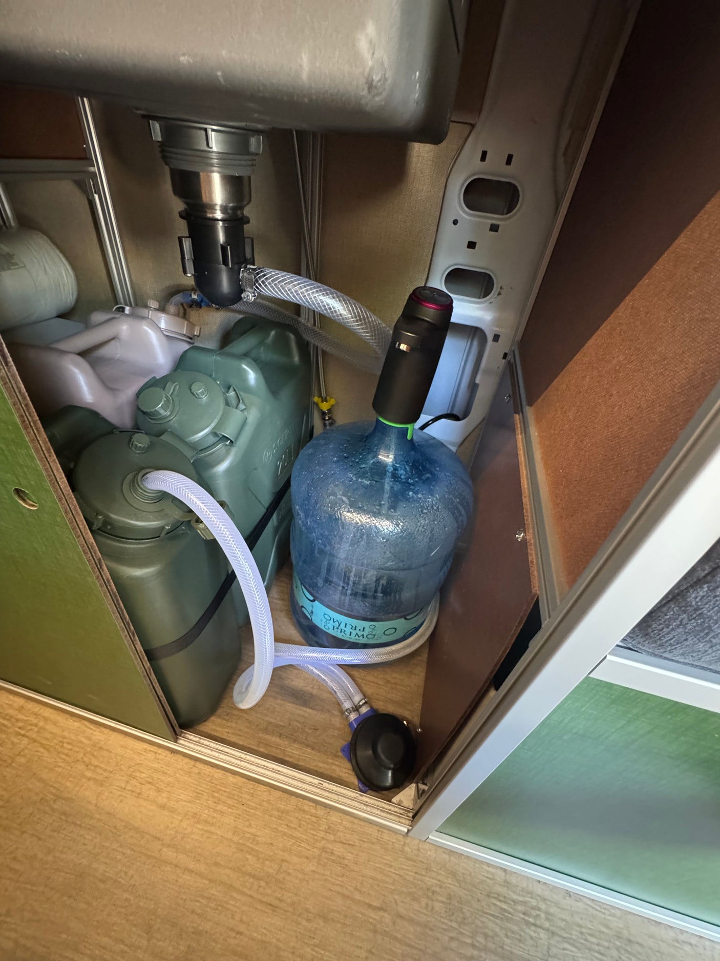 RV rental's under-sink water system: fresh water bottle, waste tank, and pumps for efficient mobile living.