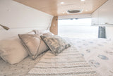 RV rental: Interior of a bright van bedroom with a comfortable bed and panoramic water view, including a bridge.