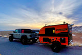 Jeep Gladiator towing a Sunray Sport teardrop camper for a scenic rv rental adventure at sunset in a vast landscape.
