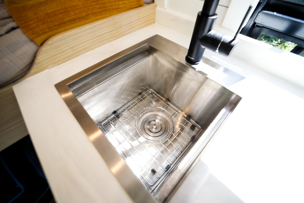 Close-up of a spotless stainless steel kitchen sink with a protective grid and sleek black faucet, a key feature in this RV rental.
