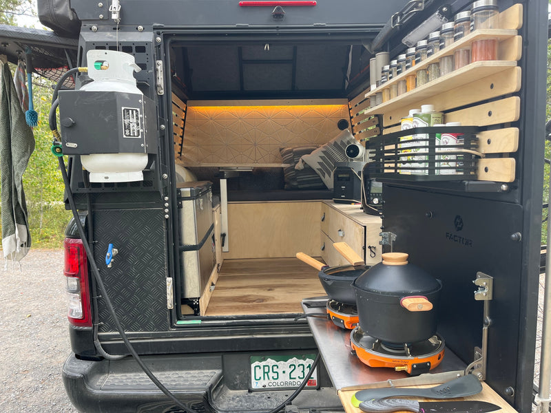Rear view of a custom camper, ideal for an **rv rental** adventure. Features an outdoor kitchen with propane, a spice rack, and a cozy interior with a bed and storage. — photo 15