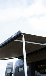 Extended Fiamma F45S awning on a dark RV rental, supported by a white pole. Perfect for shaded outdoor living.