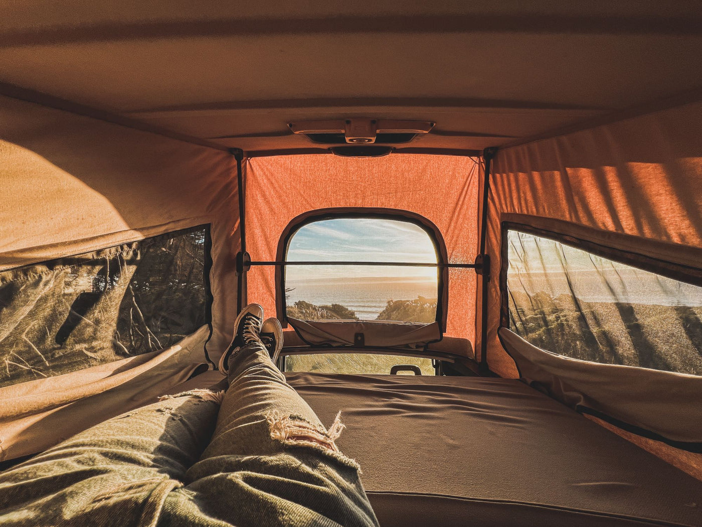  watching a vibrant sunset through the rear window. Cozy van life.|POV from an RV rental bed: legs stretched out — photo 9