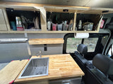 Compact RV rental kitchen with butcher block counter, sink, storage, and paper towel holder, perfect for on-the-go meals.