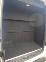 Inside a custom-built RV rental cargo van, featuring a black-lined storage area with built-in shelves and an overhead light.