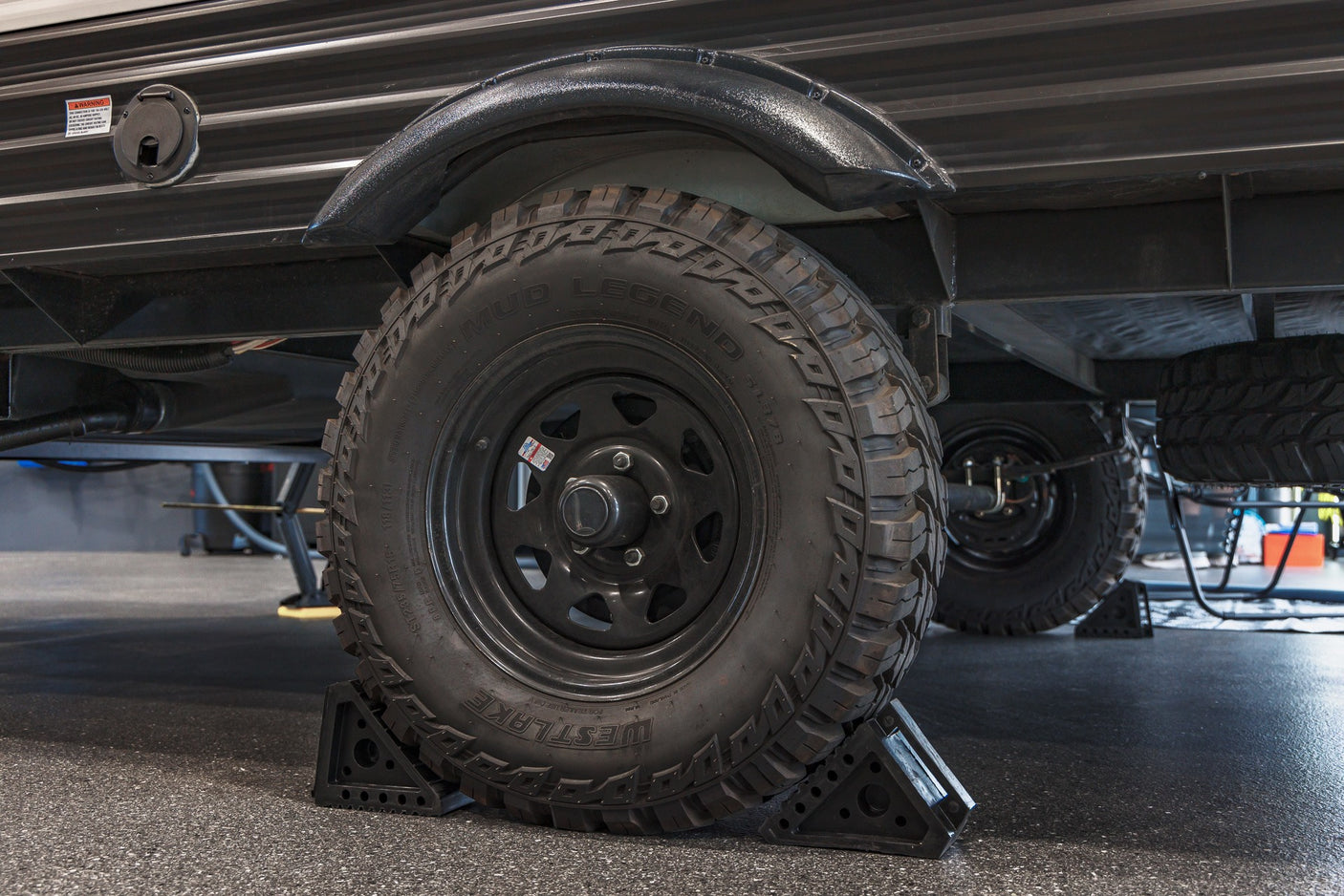 Rugged RV rental trailer with Westlake Mud Legend off-road tires, securely chocked for stability.