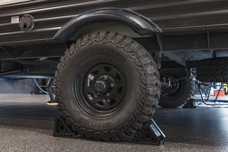 Rugged RV rental trailer with Westlake Mud Legend off-road tires, securely chocked for stability.