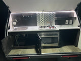 RV rental's outdoor galley: sink, two-burner stove, microwave, and outlets, perfect for convenient campsite cooking.