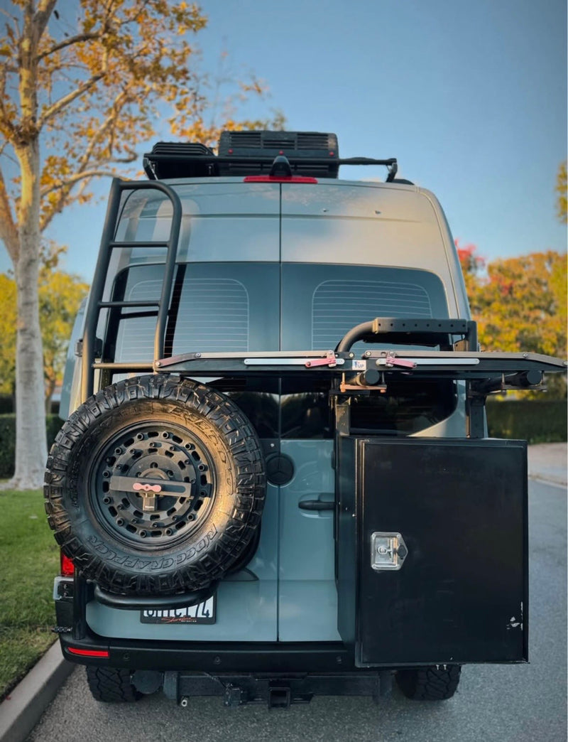 Back view of a gray camper van rv rental, showcasing its rear-mounted spare tire, ladder, and side storage box for your next trip. — photo 10