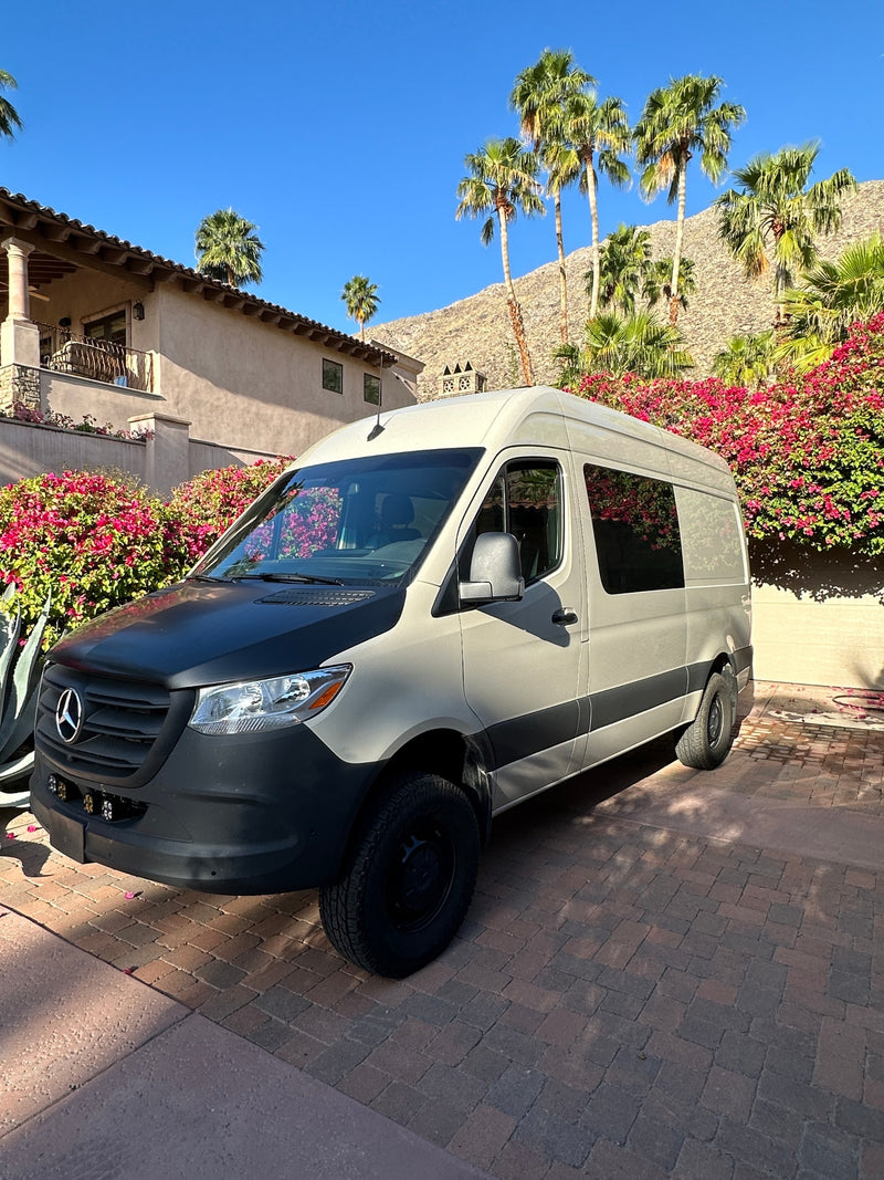 Mercedes Sprinter RV rental on brick driveway, house, palm trees, and pink bougainvillea in background. — photo 12