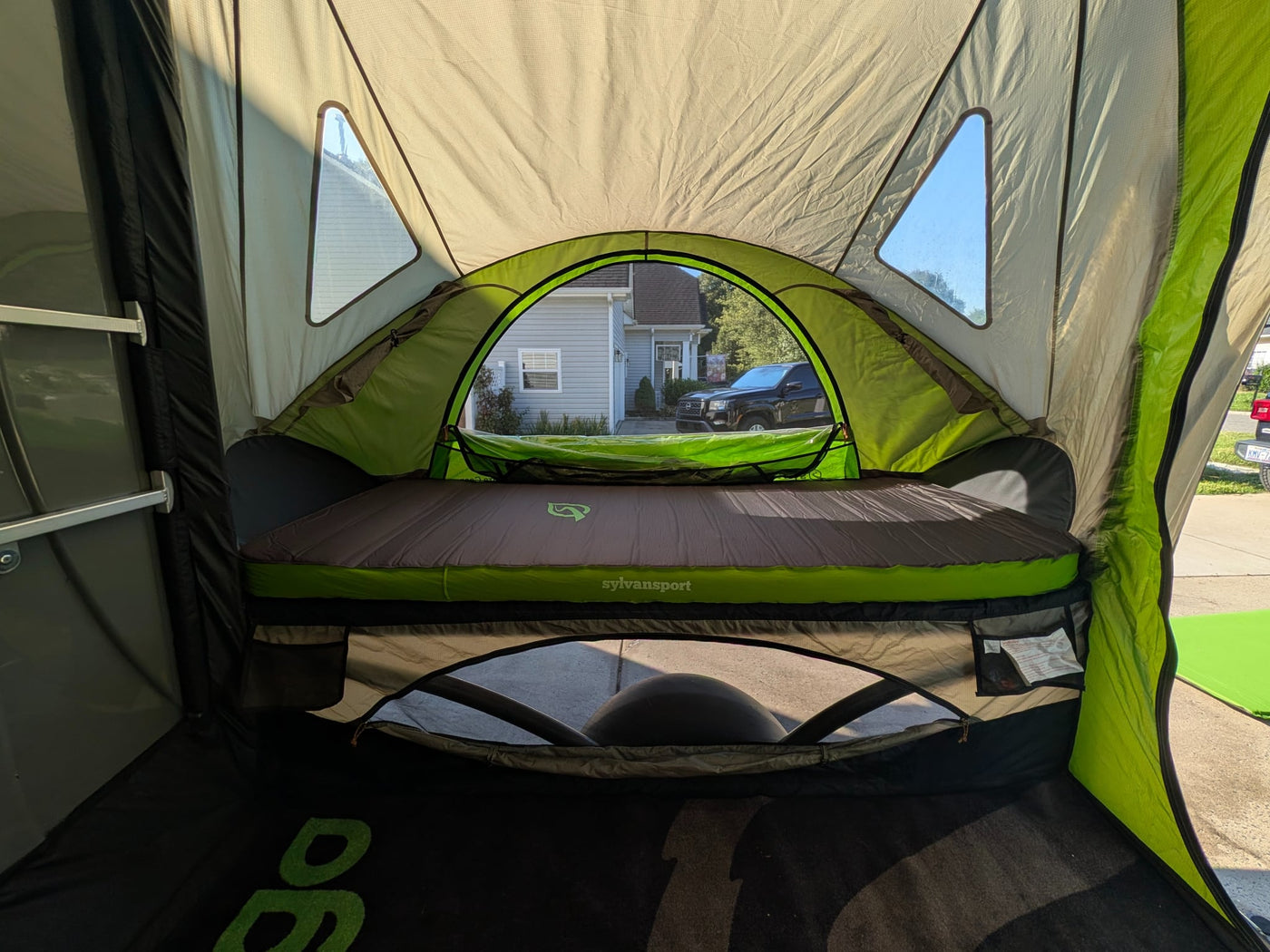  parked on a driveway. This compact camper/gear hauler is gray with a green front.|A green SylvanSport tent annex — photo 12