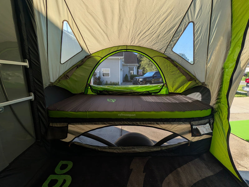  parked on a driveway. This compact camper/gear hauler is gray with a green front.|A green SylvanSport tent annex — photo 12
