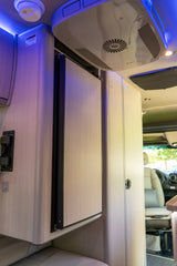 Inside a modern **rv rental**, featuring a closed refrigerator, ceiling-mounted AC unit, smoke detector, and ambient purple lighting.