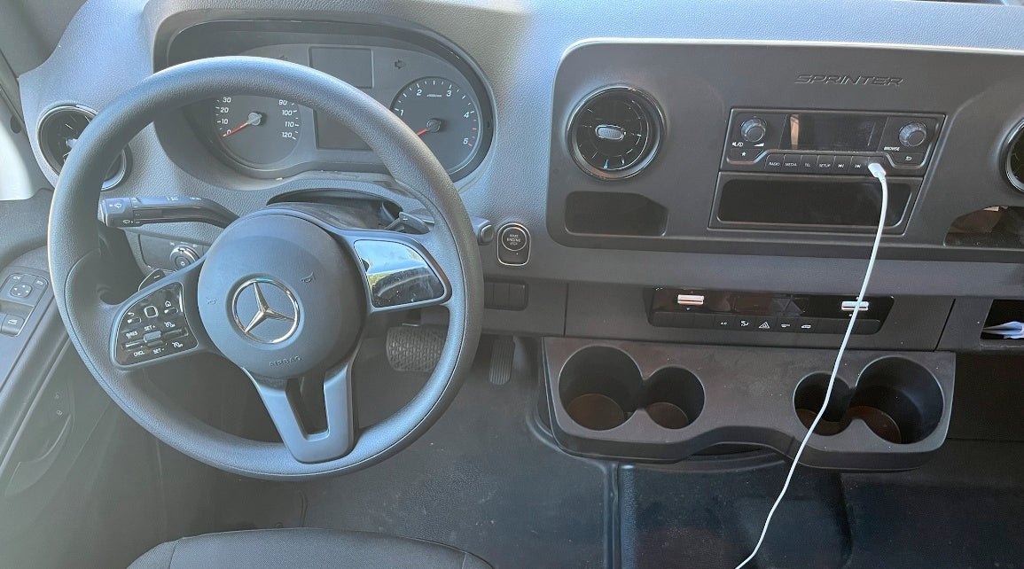 RV rental interior: Mercedes-Benz Sprinter dashboard, steering wheel, instrument cluster, radio, and cupholders.