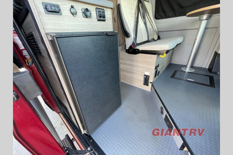  and counter. Light-colored passenger seating visible.|This RV rental interior shows a convertible bed with textured beige cushions — photo 11