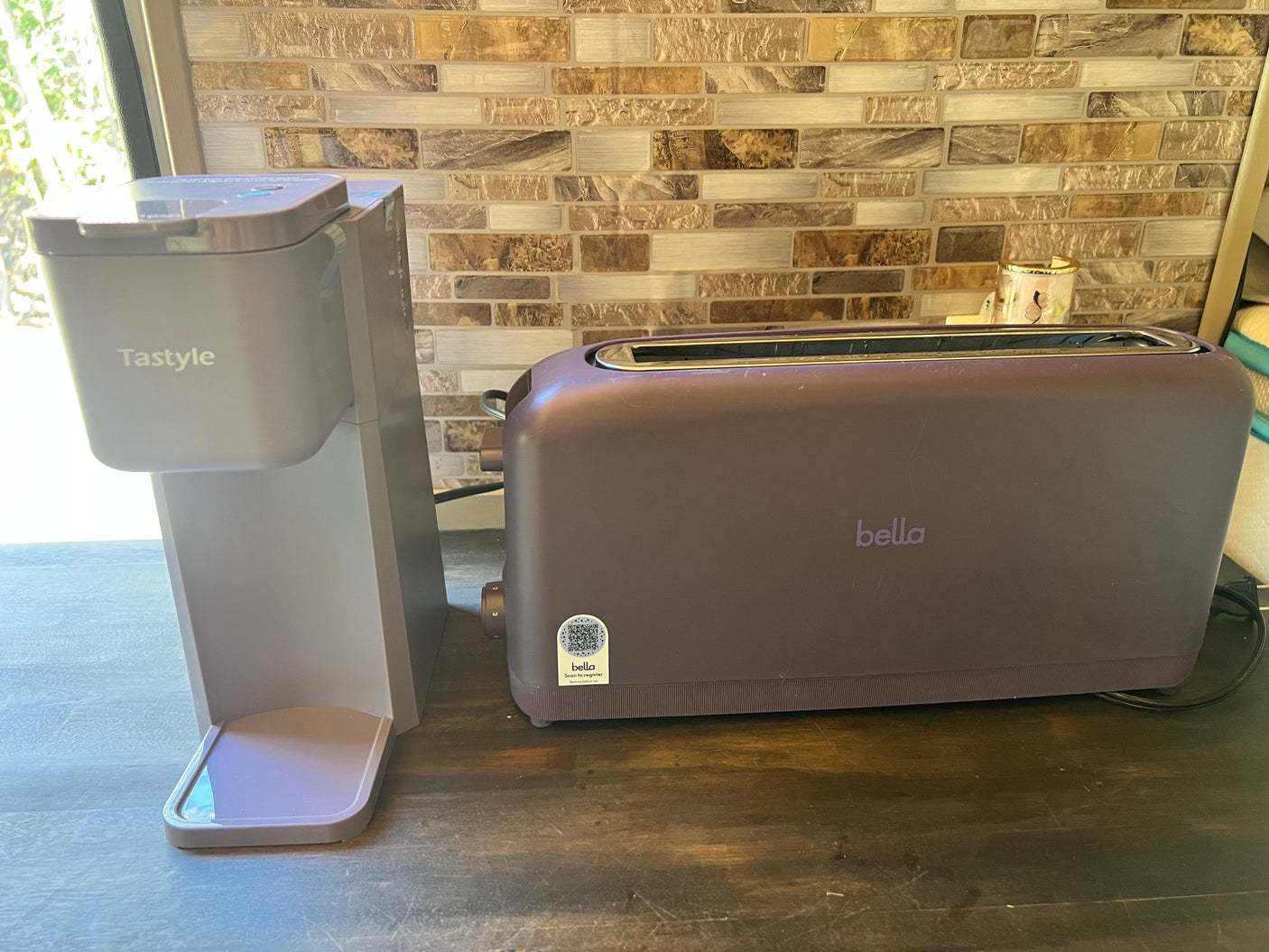 RV rental kitchen showing a gray Tastyle coffee maker and a purple Bella toaster on a dark countertop, ready for use.