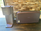 RV rental kitchen showing a gray Tastyle coffee maker and a purple Bella toaster on a dark countertop, ready for use.