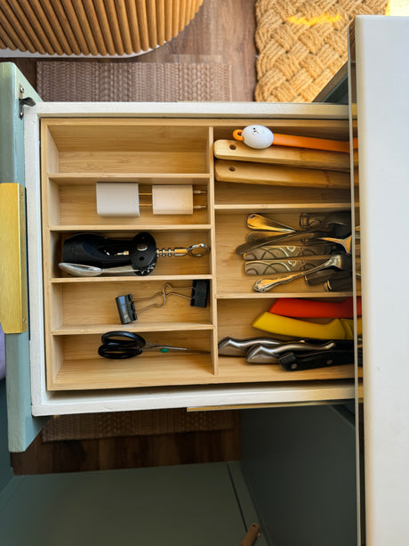 Organized kitchen drawer in an RV rental, filled with utensils, chargers, and knives, optimizing compact space.