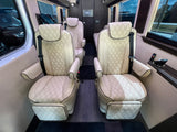 Luxury RV rental interior: Four cream-colored, diamond-quilted leather captain's chairs, wood floor, and modern controls.