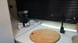 Enjoy amenities like a Keurig coffee maker, mugs, and a modern black faucet on this bright RV rental kitchen counter.