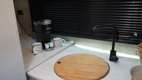 Enjoy amenities like a Keurig coffee maker, mugs, and a modern black faucet on this bright RV rental kitchen counter.