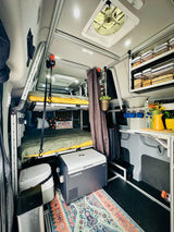 Cozy RV rental interior featuring bunk beds, a Dometic fridge, compact kitchen, and smart storage solutions for travel.