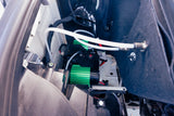 Auxiliary air compressor system with green housing & white tubing, installed in an RV rental's rear compartment.