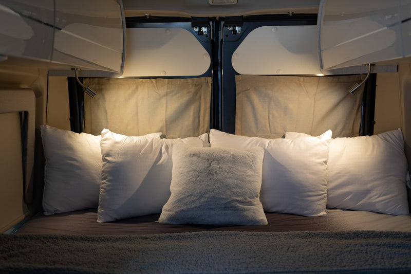 parked outdoors with a bike rack and pop-top.|Plush pillows and reading lights create a cozy RV rental bedroom. Overhead cabinets complete this comfortable — photo 16