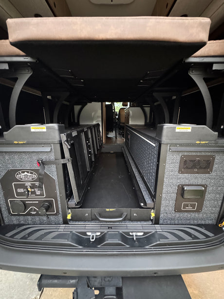 RV rental's rear storage area, featuring a Storyteller Overland utility panel, cargo lights, and a pull-out floor tray.