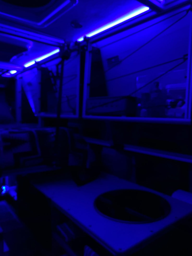 An RV rental's modern interior glows with blue light. The cabin is dark, accented by bright strips for a unique travel experience. — photo 13