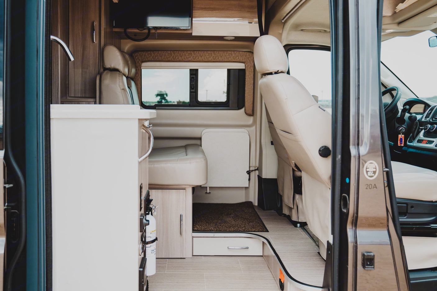 Spacious RV rental interior from the entrance, showing beige kitchen, dinette, and cockpit area.