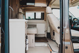 Spacious RV rental interior from the entrance, showing beige kitchen, dinette, and cockpit area.