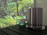 RV rental indoor scene: Portable stove, patterned glass on table, with a blurred forest projected for ambiance.