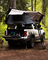 White pickup with rooftop tent & camp gear, perfect for overland adventure. Consider this alternative to RV rental.