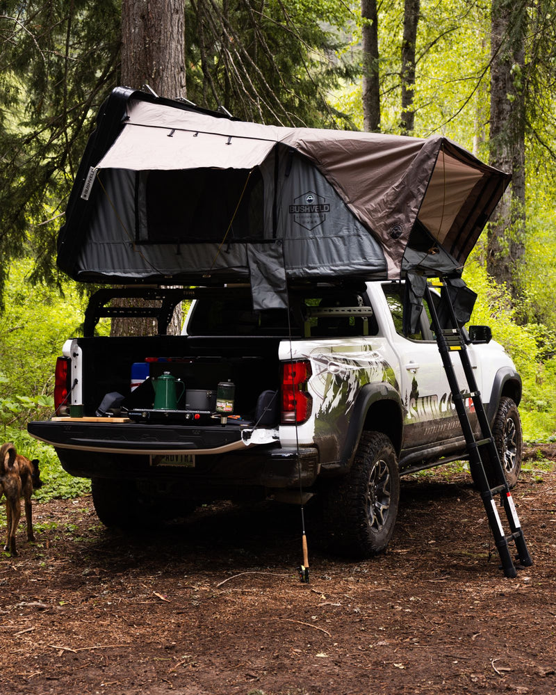  perfect for overland adventure. Consider this alternative to RV rental.|Camping truck with rooftop tent and gear in forest campsite — photo 4
