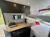 Compact rv rental interior featuring bunk beds, a modern kitchenette, and stylish overhead cabinets, perfect for van life.