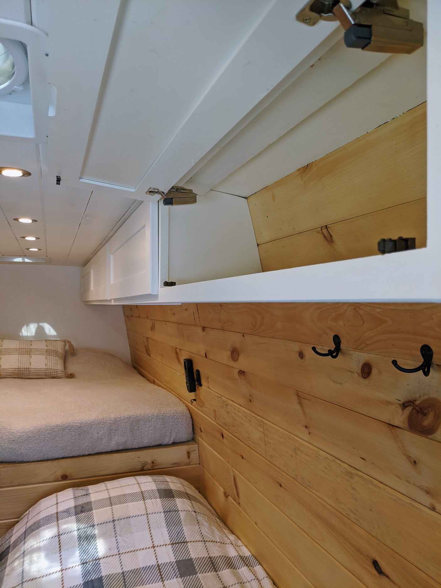 RV rental: Bright interior featuring stacked beds, natural wood paneling, and white overhead storage cabinets.