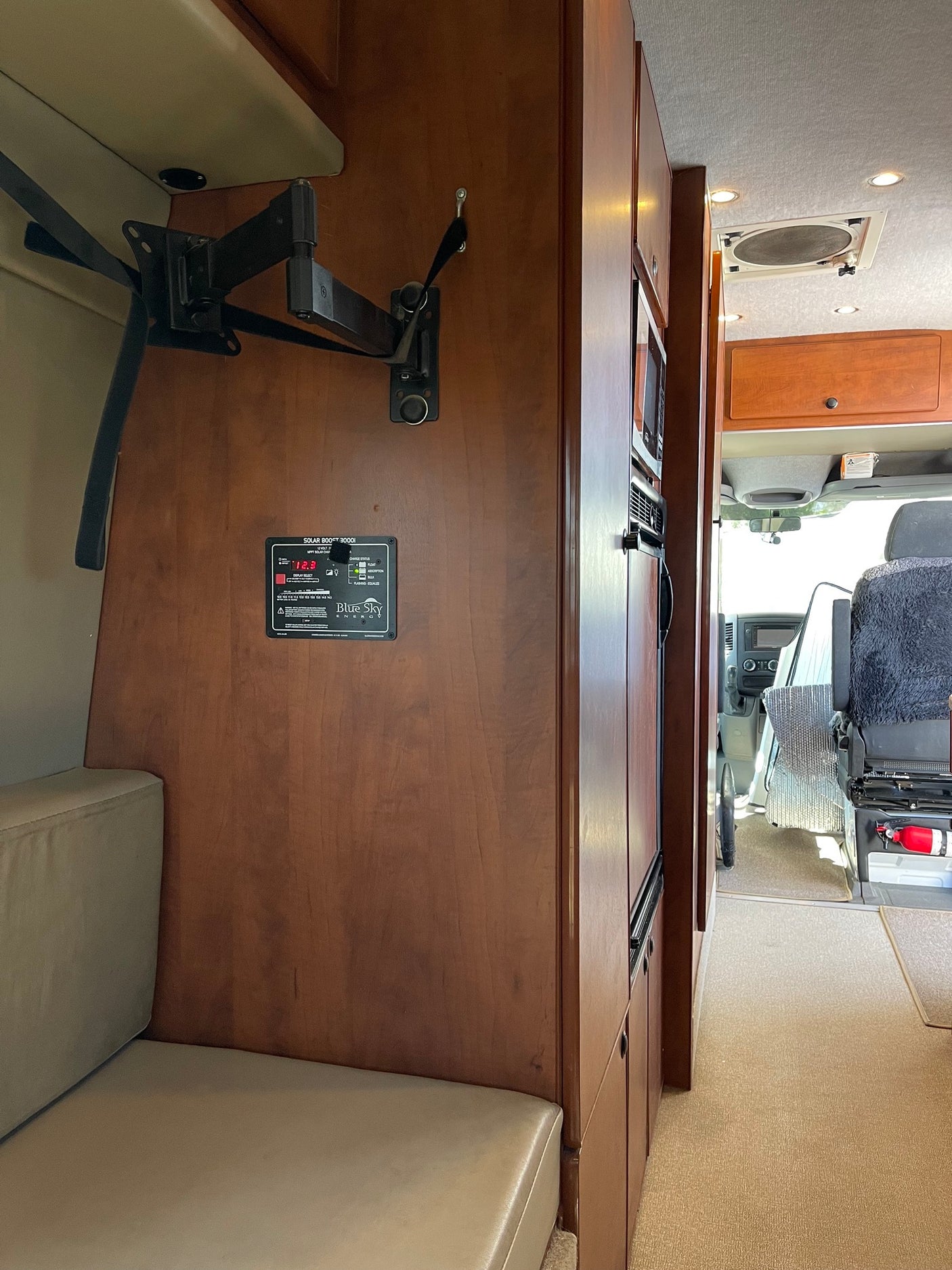Inside an RV rental: a TV mount, solar monitor, fridge, and seating area. Ready for your next adventure.