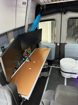 RV rental's interior: dual monitors, pull-out desk, and portable toilet create a versatile mobile office and living space.