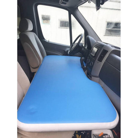 RV rental van's front cabin with a blue inflatable mattress laid out for sleeping, converting the space into a bed.
