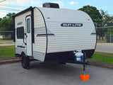Compact white "SUN LITE" travel trailer rv rental with awning, propane tank, and rugged tires, parked on asphalt.