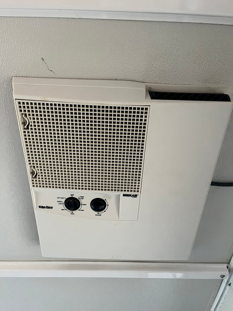 Overhead Duo-Therm Briskair RV AC unit in an RV rental, featuring accessible controls for fan and temperature.