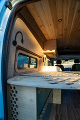 Explore this custom **rv rental** interior. Features a warm wooden ceiling, unique perforated bed platform, and cozy fabric walls.