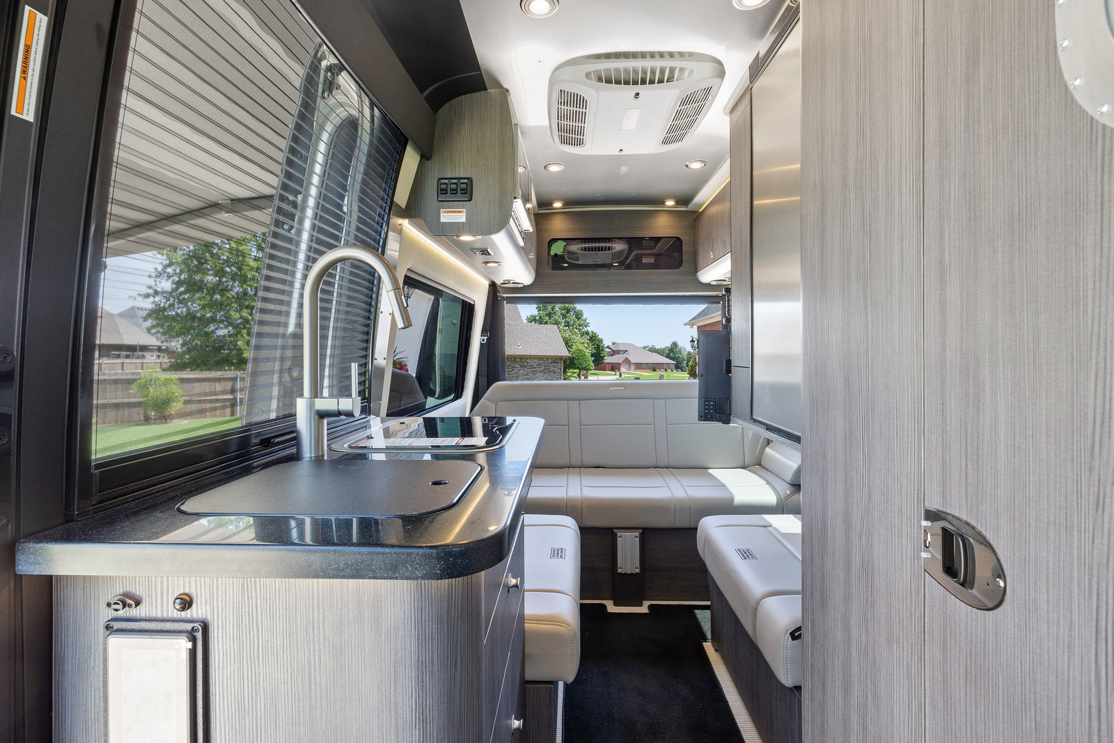 Spacious RV rental interior featuring a modern kitchenette, lounge seating, and large windows for comfortable mobile living.
