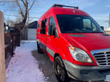Bright red RV rental parked in winter, showcasing roof-mounted solar panels. Ideal for your next camper van adventure.