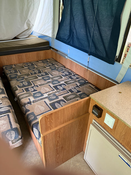 Inside this RV rental: a practical pop-up camper layout with comfortable bunk and lounge beds, and essential amenities.