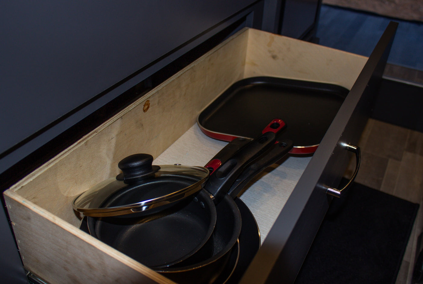 Organized rv rental kitchen drawer with various cooking pans and a griddle, ready for your meals.