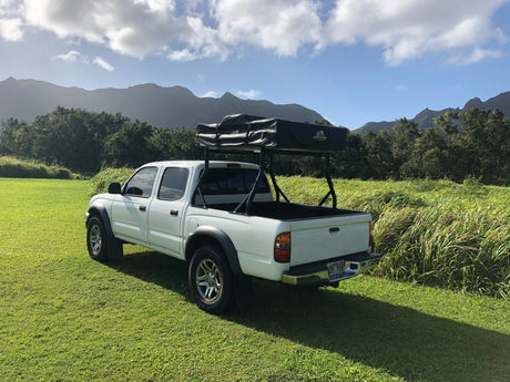 Explore Hawaii's beauty! White Tacoma truck with a Tuff Stuff rooftop tent, ready for your RV rental adventure in the mountains.