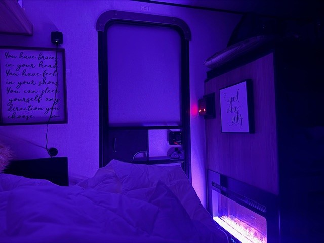 Cozy rv rental interior: purple light, comfy bed, electric fireplace, and inspiring quotes create a relaxing bedroom vibe. — photo 2