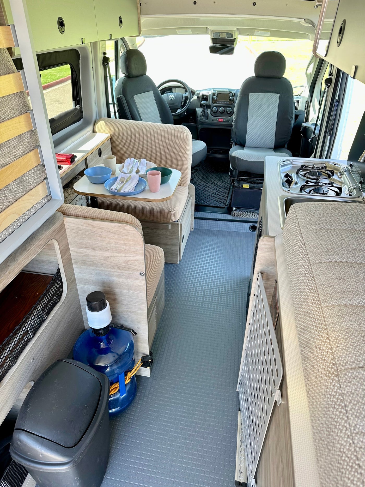 View inside an rv rental: functional camper van layout with kitchen, dining, front seats, and rear bed frame visible. — photo 10